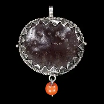 Pendant amulet of a sea-bean seed with a coral bead, mounted in silver, Spain, 1800-1899