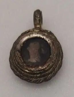 Silver-gilt niello pendent reliquary medalion with a woman's head in profile on one side and a guilloche knot 