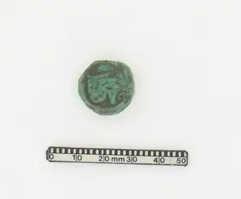A circular amulet with a wedjat eye on one side and a depiction of Bes on the other